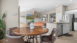 A modern kitchen with white cabinets, stainless steel appliances, and a dining area with a wooden table and leather chairs. - La Quinta Desert Haven Luxe Stay w/ Private Pool, Hot Tub, Pool Table (La Quinta)