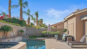 A pool area with lounge chairs, a table, and umbrellas.