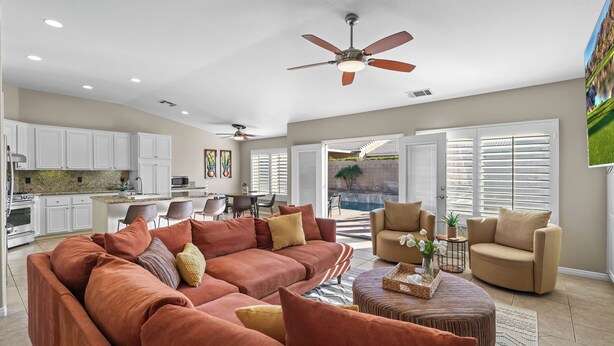 A spacious living area with a large sofa, a coffee table, and a ceiling fan.