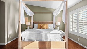 A four-poster canopy bed with a wooden headboard, white bedding, and two bedside lamps.
