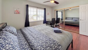 Ein Schlafzimmer mit Bett, Schreibtisch, Stuhl und Deckenventilator.