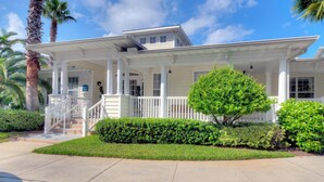 A two-story house with a covered porch, white columns, and a small staircase leading to the entrance. - Beautifully Decorated Condo, St. Simons Island, 8 minutes to Beach, Heated Pool (St. Simons Island)