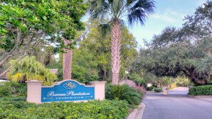 A sign for Barnes Plantation Condominium surrounded by lush greenery and palm trees. - Beautifully Decorated Condo, St. Simons Island, 8 minutes to Beach, Heated Pool (St. Simons Island)