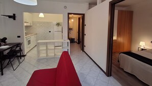 A modern apartment with a dining area, kitchen, and a bedroom.