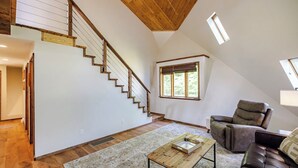 Un vaste espace de vie agrémenté d’un escalier en bois, d’un canapé en cuir et d’une table basse.
