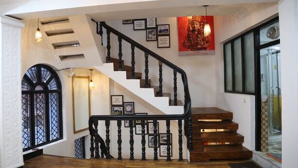 A staircase with wooden steps and black balusters, flanked by framed quotes on the walls.