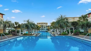 Ein Swimmingpool mit Liegestühlen und Palmen, umgeben von Gebäuden.
