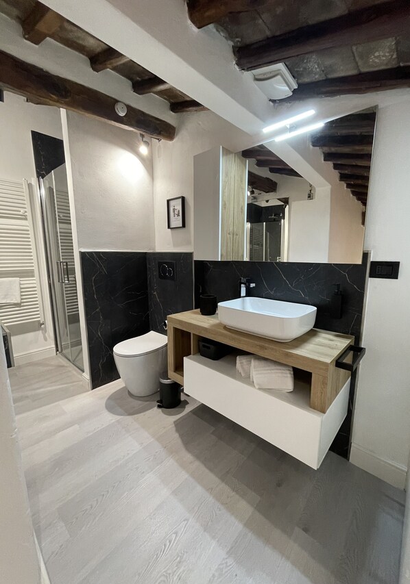 Ein modernes Badezimmer mit einem weißen Waschbecken, schwarzen Marmorwänden und Holzelementen.