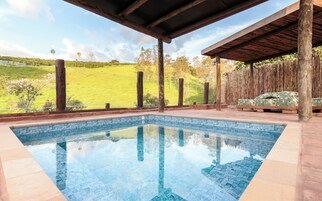 Piscina com vista clara para uma paisagem verde e área de deck de madeira.