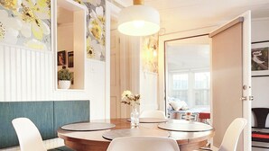 A dining area with a round table, white chairs, and a vase of flowers. - Stylish Douglas Retreat - Steps from Dunes Resort! (Douglas)
