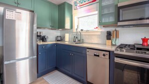 A kitchen with green cabinets, a stainless steel refrigerator, a dishwasher, a stove, and a window with a view of the outdoors. - Stylish Douglas Retreat - Steps from Dunes Resort! (Douglas)