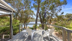 A wooden deck with white chairs overlooking a lake, surrounded by trees. - Paradise Retreat Lakehouse  - Jamieson - Sleeps 10 (Jamieson)