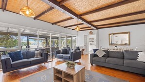 A spacious living area with a large window overlooking a scenic landscape, a wooden ceiling, and a modern fireplace. - Paradise Retreat Lakehouse  - Jamieson - Sleeps 10 (Jamieson)