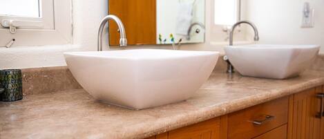A bathroom with two white vessel sinks, a wooden vanity, and a mirror.