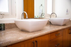 Une salle de bain avec deux vasques blanches, un meuble-lavabo en bois et un miroir.