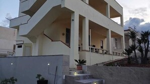 A modern multi-story building with a flat roof, a central staircase, and a small garden area with artificial grass and potted plants. - Star Apartment, Alcamo Marina, 3 bedrooms, swimming pool, view and fun... enjoy (Alcamo)