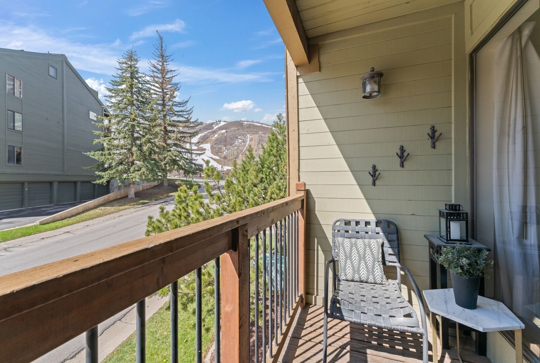 A balcony with a wooden railing, a table with a potted plant, and a chair.