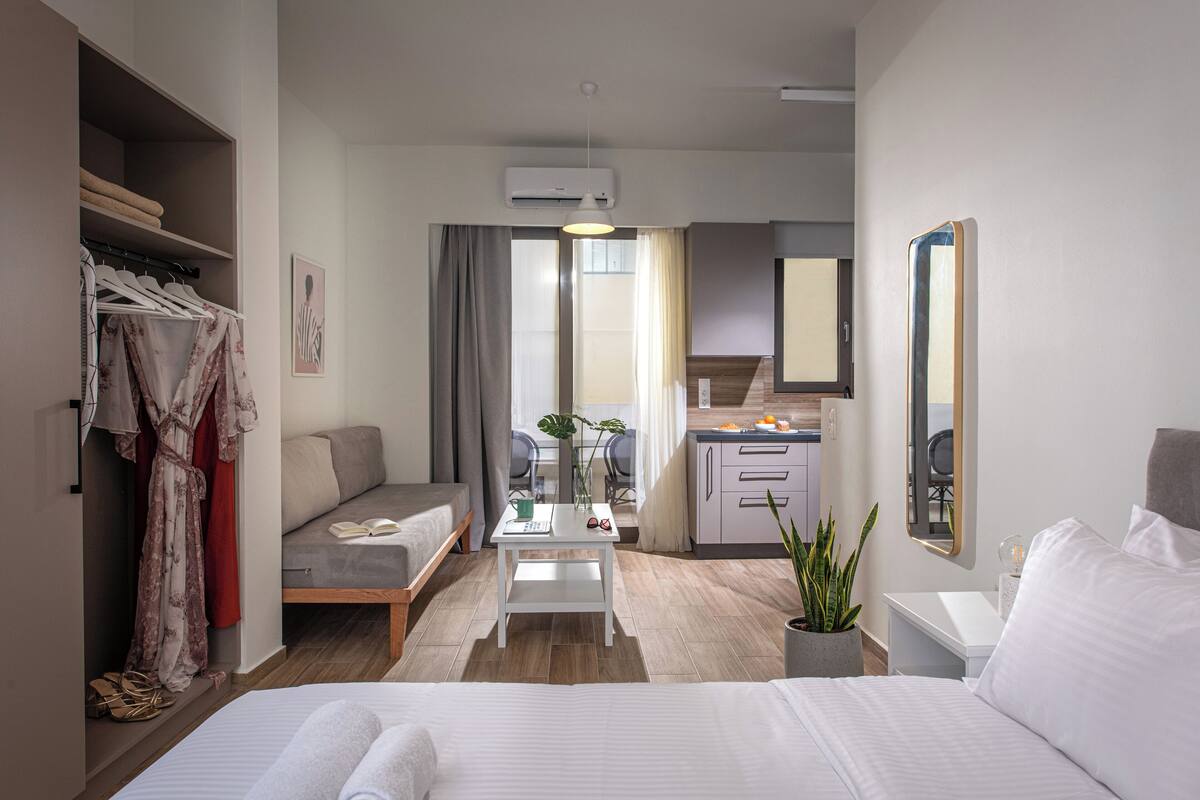 Une chambre d’hôtel moderne équipée d’un lit, d’un coin salon, d’une kitchenette et d’une armoire.