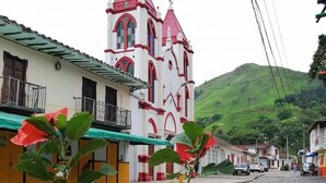 A street with a church featuring a bell tower, a cobblestone road, and a green hill in the background. - VILLA CATALINA FARM WITH SWIMMING POOL AND JACUZZI NEAR LA PINTADA  (Santa Bárbara)