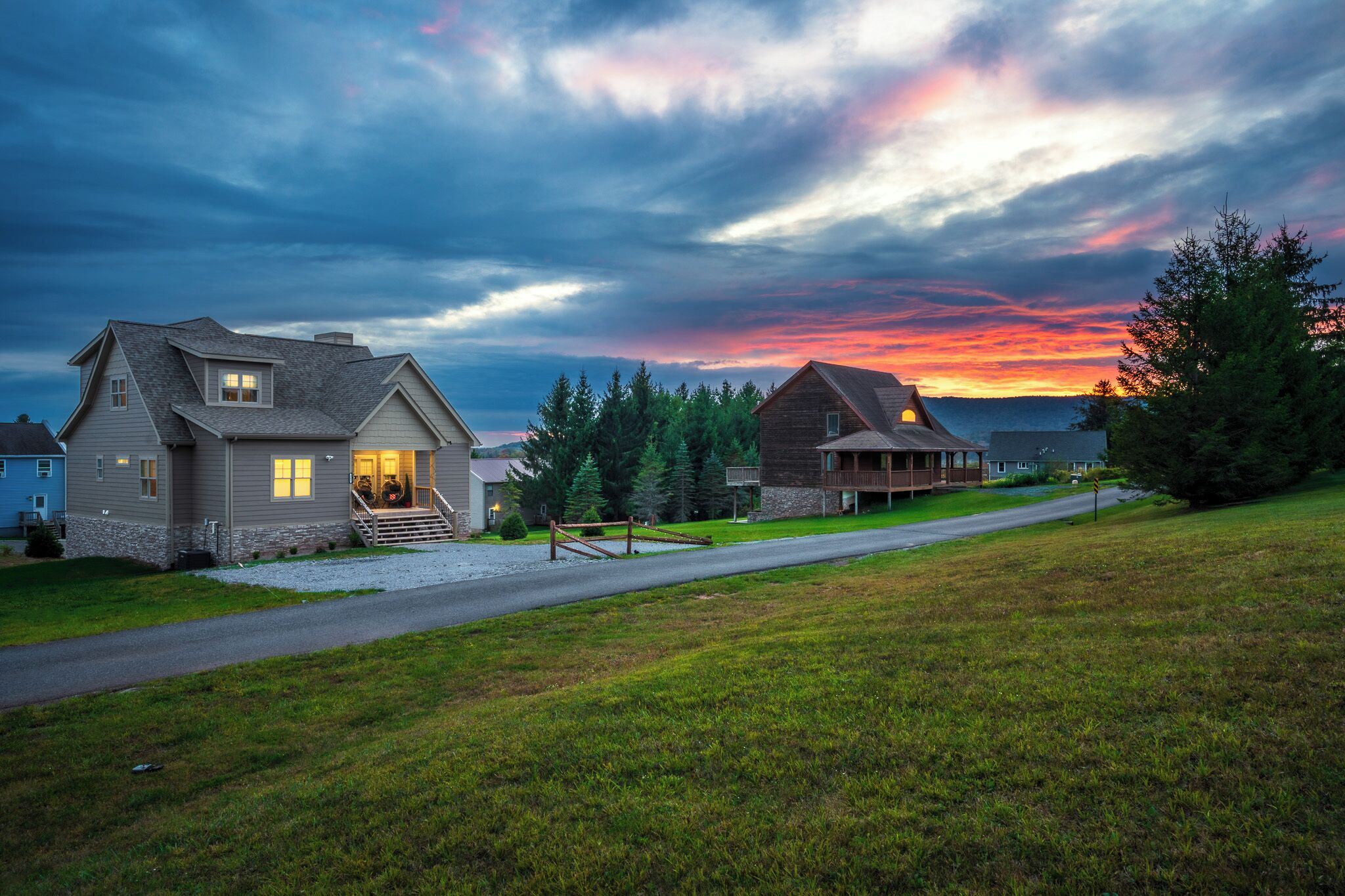A residential area with houses, a driveway, and a grassy field.
