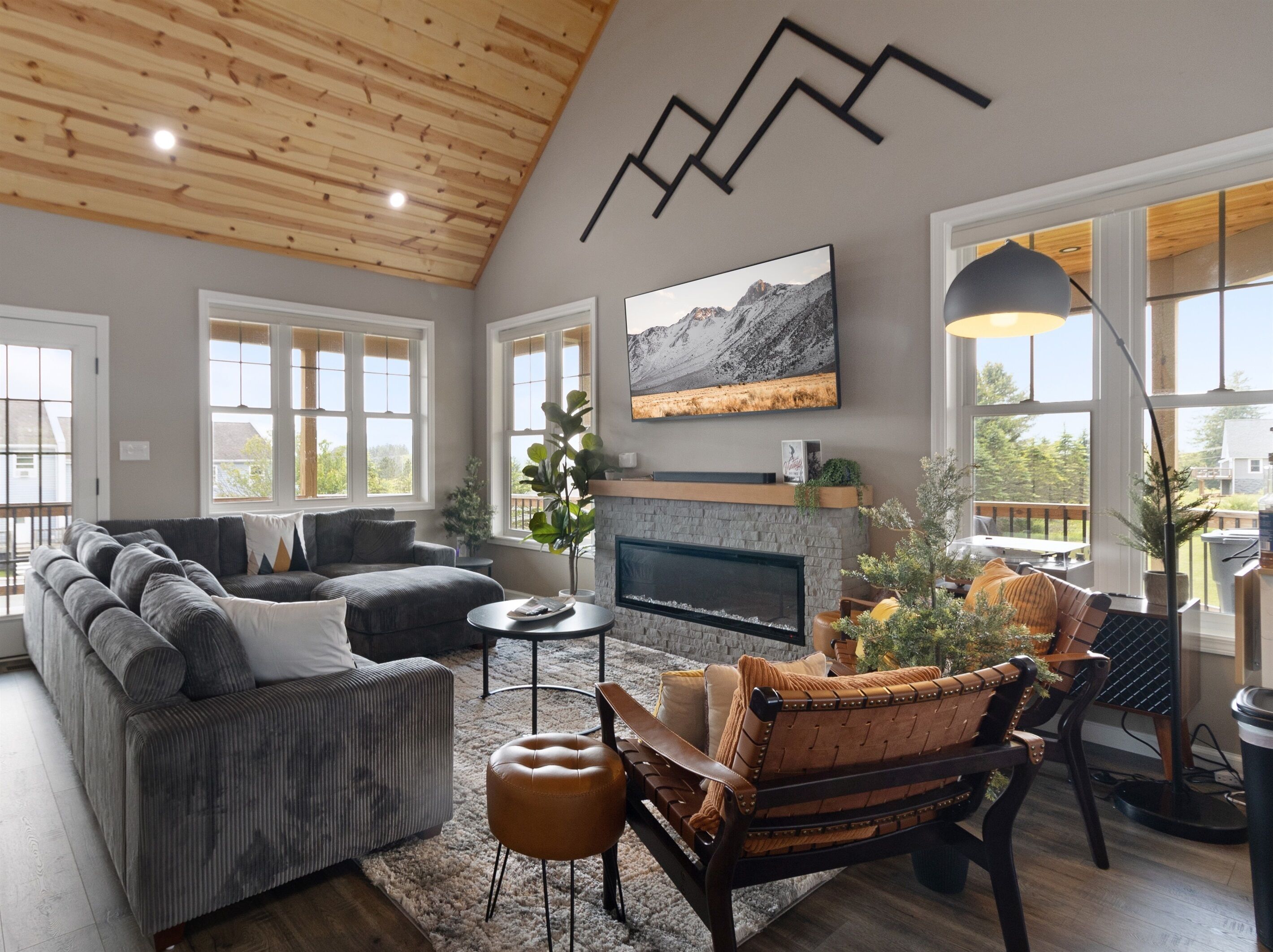A modern living room with a fireplace, large windows, and a high ceiling.