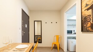 Ein Essbereich mit einem Holztisch, gedeckt für zwei Personen, einem Spiegel an der Wand und einer durchgehenden Tür einsehbarer Küche.