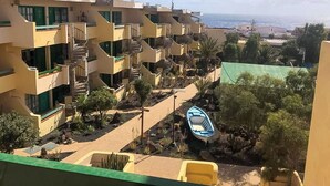 Un hotel de varios pisos con balcones, zona de piscina y vista al mar.