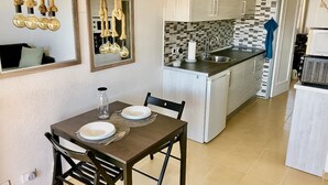 Cocina compacta con comedor, que incluye un protector contra salpicaduras de azulejos, un microondas y un lavamanos.