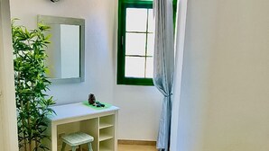 Una habitación pequeña con escritorio, silla y un tapete verde en el suelo.