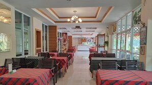Un restaurante con varias mesas cubiertas de manteles escoceses, sillas de madera y piso de baldosas.