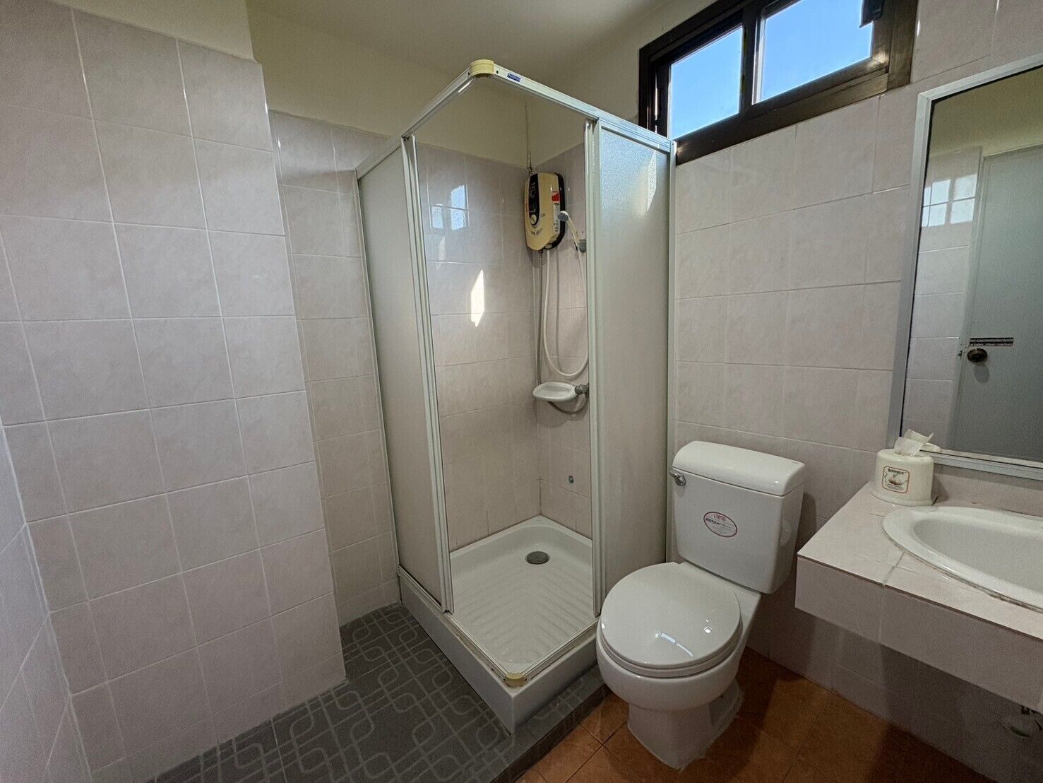 Un baño con ducha de vidrio, inodoro y lavamanos.