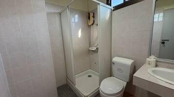 Un baño con ducha de vidrio, inodoro y lavamanos.
