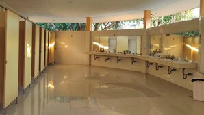 Un baño amplio y moderno con varios lavamanos, un espejo grande y un suelo de baldosas impecable.
