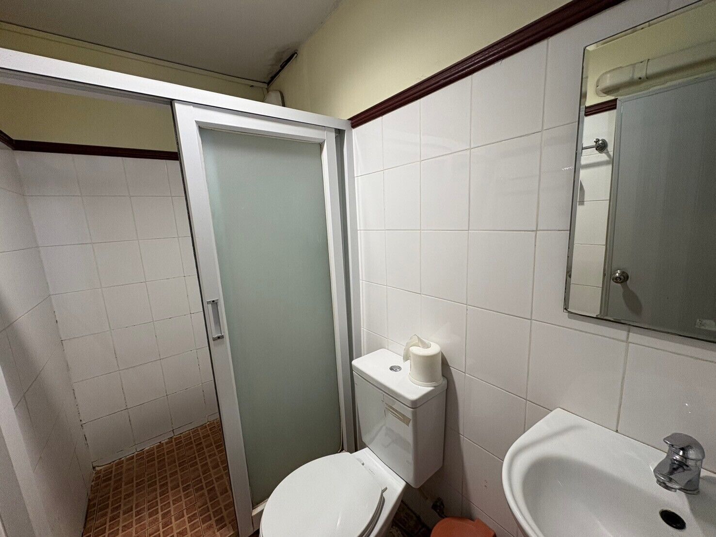 A small bathroom with a toilet, sink, and mirror.