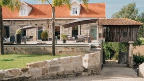 A stone building with a red-tiled roof, outdoor seating, and a stone wall. - Casa da Eira - Rural Retreat (Vilar)