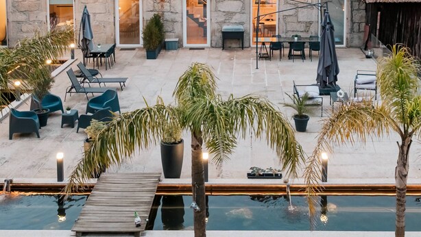 A stone building with a red roof, outdoor seating, a pool, and palm trees. - Casa da Eira - Rural Retreat (Vilar)