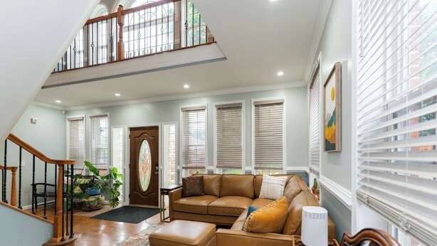 A spacious living room with a high ceiling, a staircase, and large windows with blinds. - National Harbor  Hideaway - Oasis /Jacuzzi w/ 4-bedroom/3-Bath  
Fort Washington (Fort Washington)