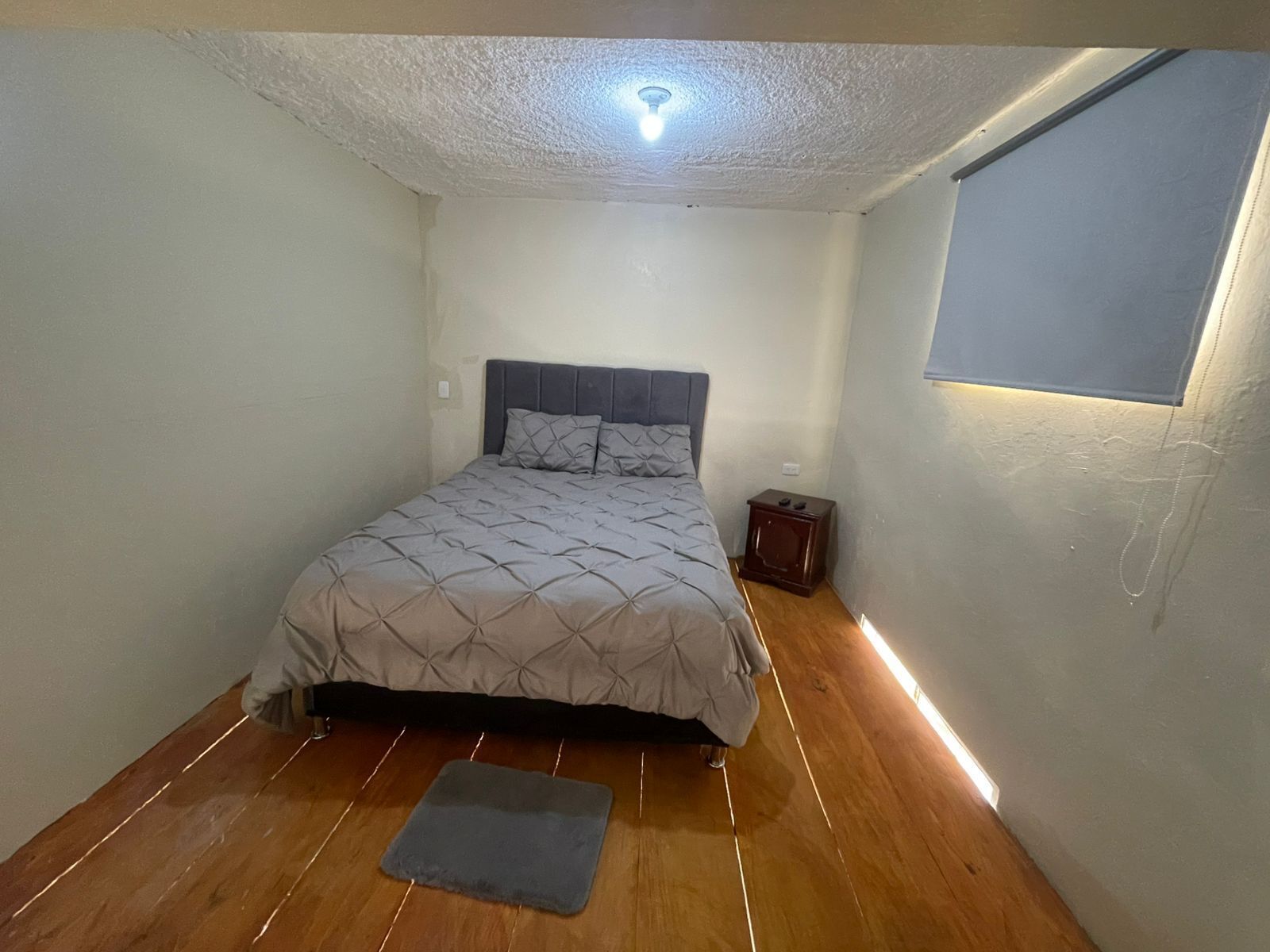 Une chambre à coucher avec un lit, une table de chevet et une fenêtre.