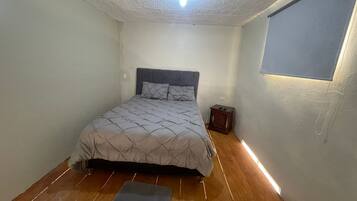 Une chambre à coucher avec un lit, une table de chevet et une fenêtre.