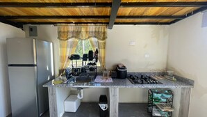 Una cocina compacta con un refrigerador de acero inoxidable, una estufa a gas y un lavamanos.