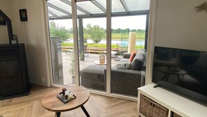 Un salon avec une porte-fenêtre coulissante donnant sur une terrasse extérieure.
