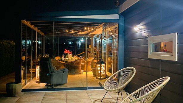 Une terrasse extérieure avec des portes vitrées, des chaises en osier et une table à manger décorée de bougies.