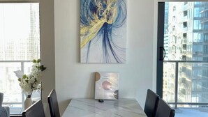 A modern dining area with a marble table, black chairs, and a large abstract painting on the wall. - *Cozy Condo/King Bed/Pool/Gym/CityViews/Walkscore 91 (Calgary)