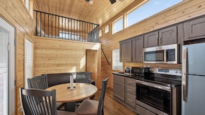 Interieur van een houten chalet met een eetgedeelte, keuken en een balkon.