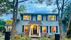 A two-story house with a front porch, a brick entryway, and a small front yard with a wooden fence. - Historic Edge of the River, Adirondacks (Willsboro)