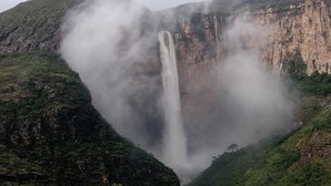 A waterfall surrounded by steep, rocky cliffs and lush greenery.