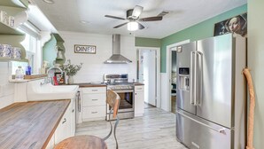 Eine moderne Küche mit Essbereich, Deckenventilator, Edelstahlkühlschrank und einem Holzessttisch.