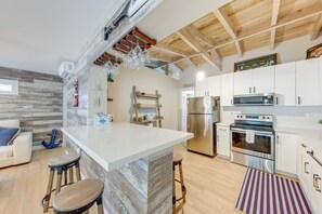 A modern kitchen with a central island, stainless steel appliances, and a wooden ceiling.