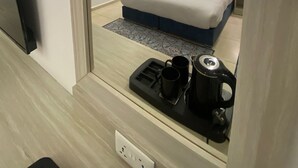 Una camera d'albergo moderna con un letto grande, una TV a schermo piatto, una macchina del caffè e una presa di corrente.