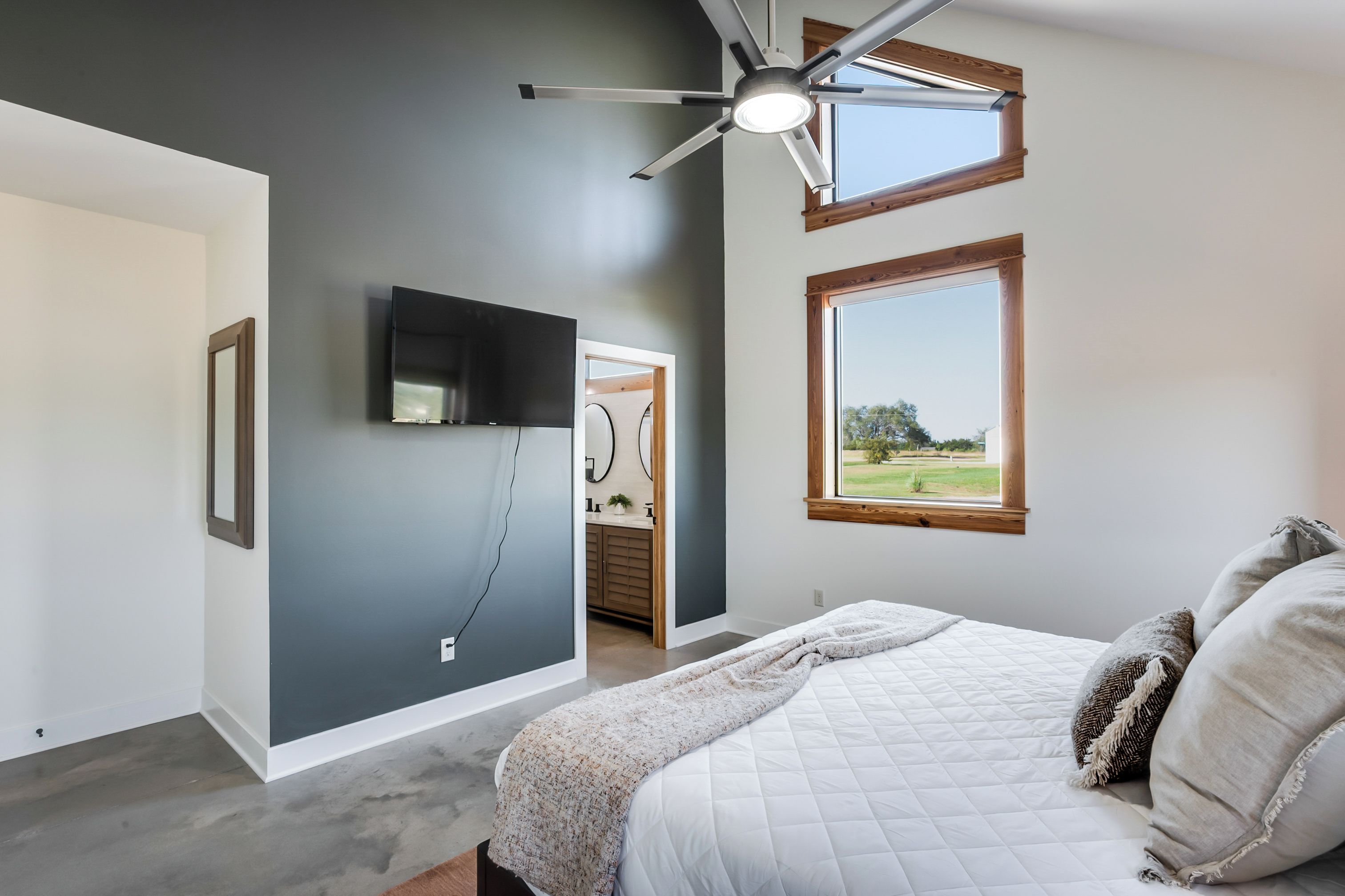 Ein Schlafzimmer mit Bett, Deckenventilator, Fernseher und Fenster mit Blick.